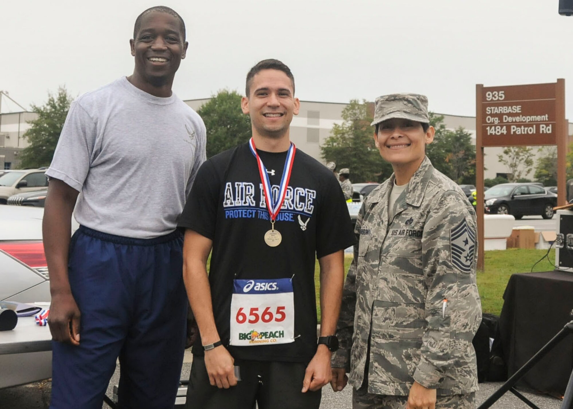 The first-place winner of this year's Falcon 5K, center, poses for a photo with Col. Patrick Campbell and Chief Master Sgt. Imelda Johnson Oct. 15, 2017. Flynn took home the first place title once again for the fifth year in a row. (U.S. Air Force photo/Senior Airman Justin Clayvon)