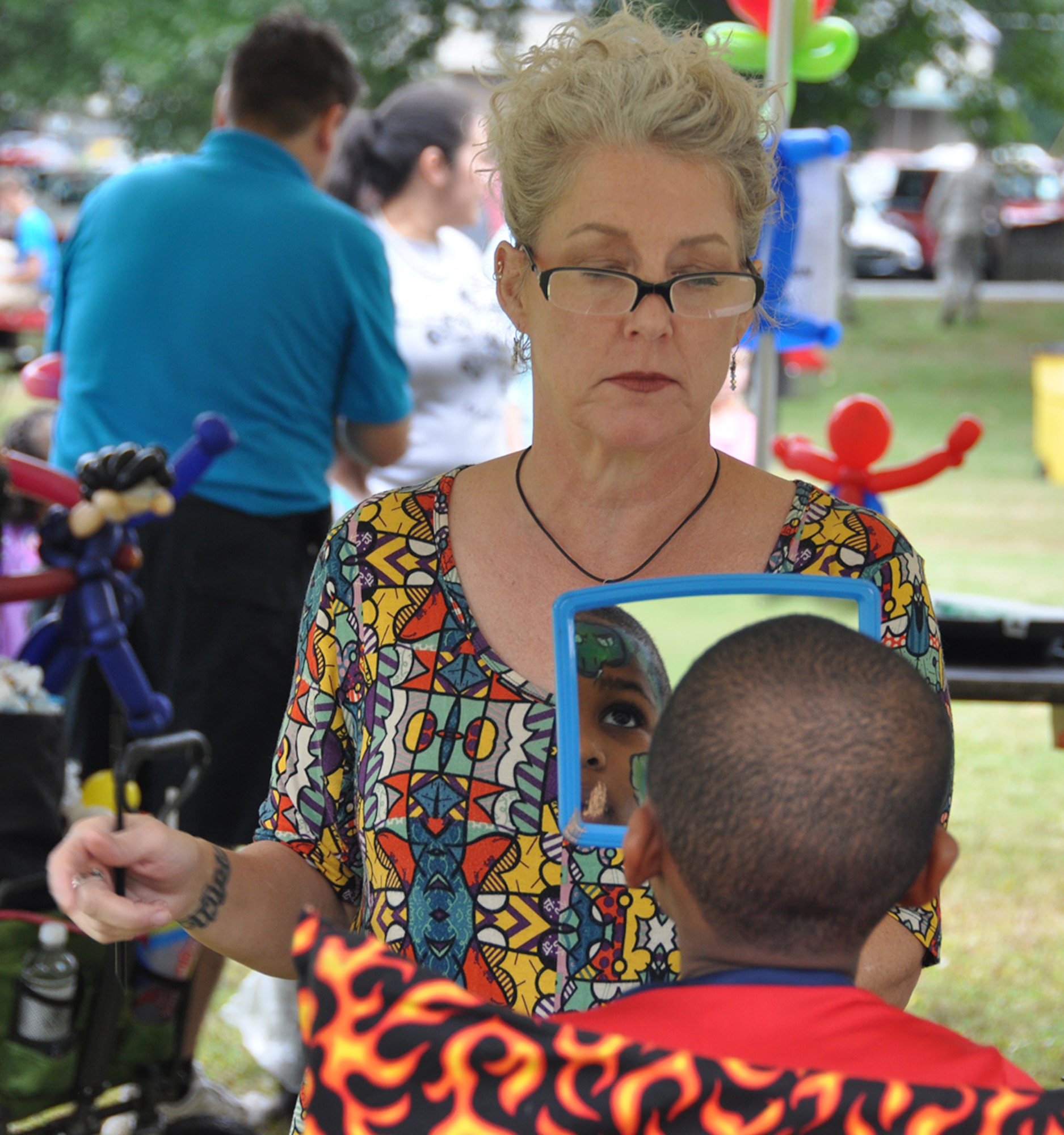 A face painter holds up a mirror to a young boy who just had his face painted at this year's Family Day Oct. 14, 2017 at Dobbins Air Reserve Base, Ga. Family Day is held here annually as a way of bringing families on base to see what their Reserve Citizen Airmen do on drill weekends. (U.S. Air Force photo/Master Sgt. James Branch)