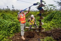 Two soldiers with shovels work with an auger.