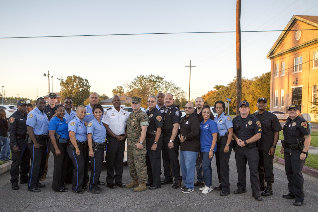 Marines, community members and officers with the New Orleans Police Department pose for a photo outside of The Village at Federal City, New Orleans, Oct. 17, 2017. “A Night Out Against Crime” is a yearly event in which Marines and police officers within the NOPD bring together community members to raise awareness of police officer presence. The event involved military and civilian officers allowing children to sit in a patrol vehicle, a pumpkin-patch dash, a prize drawing and free concession snacks for all those in attendance. (U.S. Marine Corps photo by Cpl. Dallas Johnson/Released)