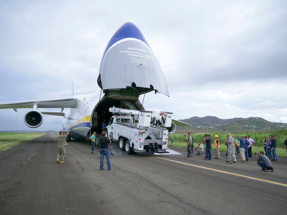 Members of the 821st Contingency Response Group help to offload line trucks from a Ukrainian Anatov 124-100m cargo transporter onto the tarmac of Jose Aponte De La Toore Airport in Ceiba, Puerto Rico, Oct. 11, 2017. The line trucks will be used to help repair the electrical grid in Puerto Rico that was destroyed after Hurricane Maria devastated the island.