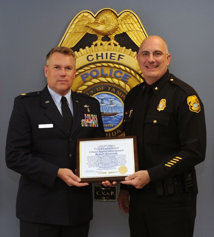 Maj. Robert Simmons (left), a reserve Medical Service Corps officer with the 45th Aeromedical Evacuation Squadron, MacDill Air Force Base, Fla., received a Citizen Appreciation Award on Oct. 19, 2017 from the Tampa Police Department Interim Chief Brian Dugan (right) for his response to a traffic accident and his subsequent life-saving actions. In July 2017, having just finished his monthly reserve training and leaving the base, Simmons witnessed a car accident that left one driver severely wounded as a result of an impaled object. Simmons was able to quickly secure the scene and administer life-saving care to the driver. (U.S. Air Force photo by Tech. Sgt. Peter Dean)