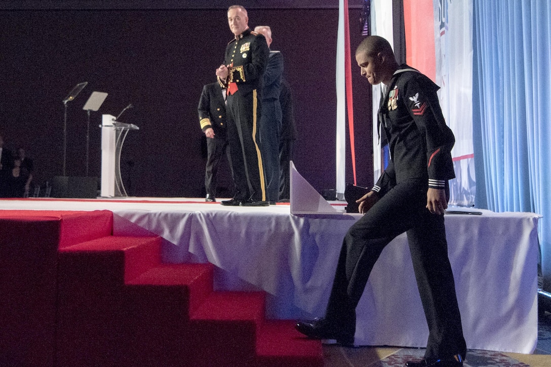 A sailor walks up the steps to the stage.