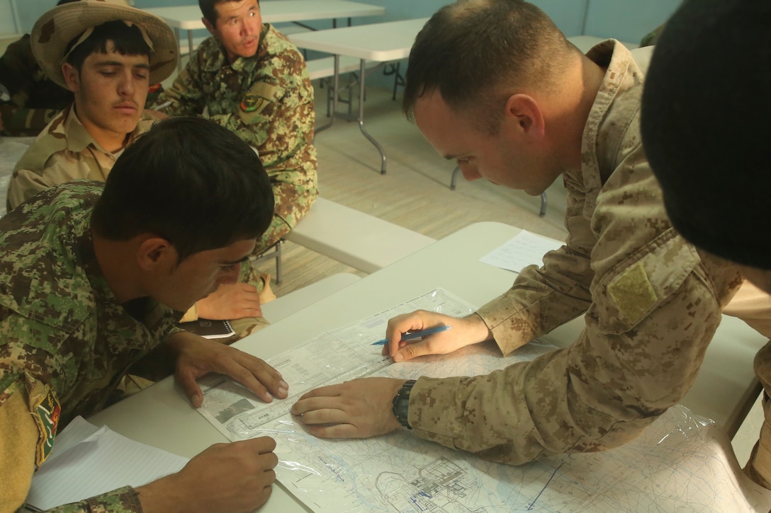 A U.S. Marine advisor with Task Force Southwest instructs Afghan National Army soldiers with Artillery Brigade, 215th Corps on proper map reading techniques during an artillery course at Camp Shorabak, Afghanistan, Oct. 21, 2017. The eight-week training program incorporates forward observers, artillery crewmen and a fire direction control team, and is designed to enhance their employment of artillery assets and gain hands-on skills with the 122mm howitzer D-30. (U.S. Marine Corps photo by Sgt. Lucas Hopkins)