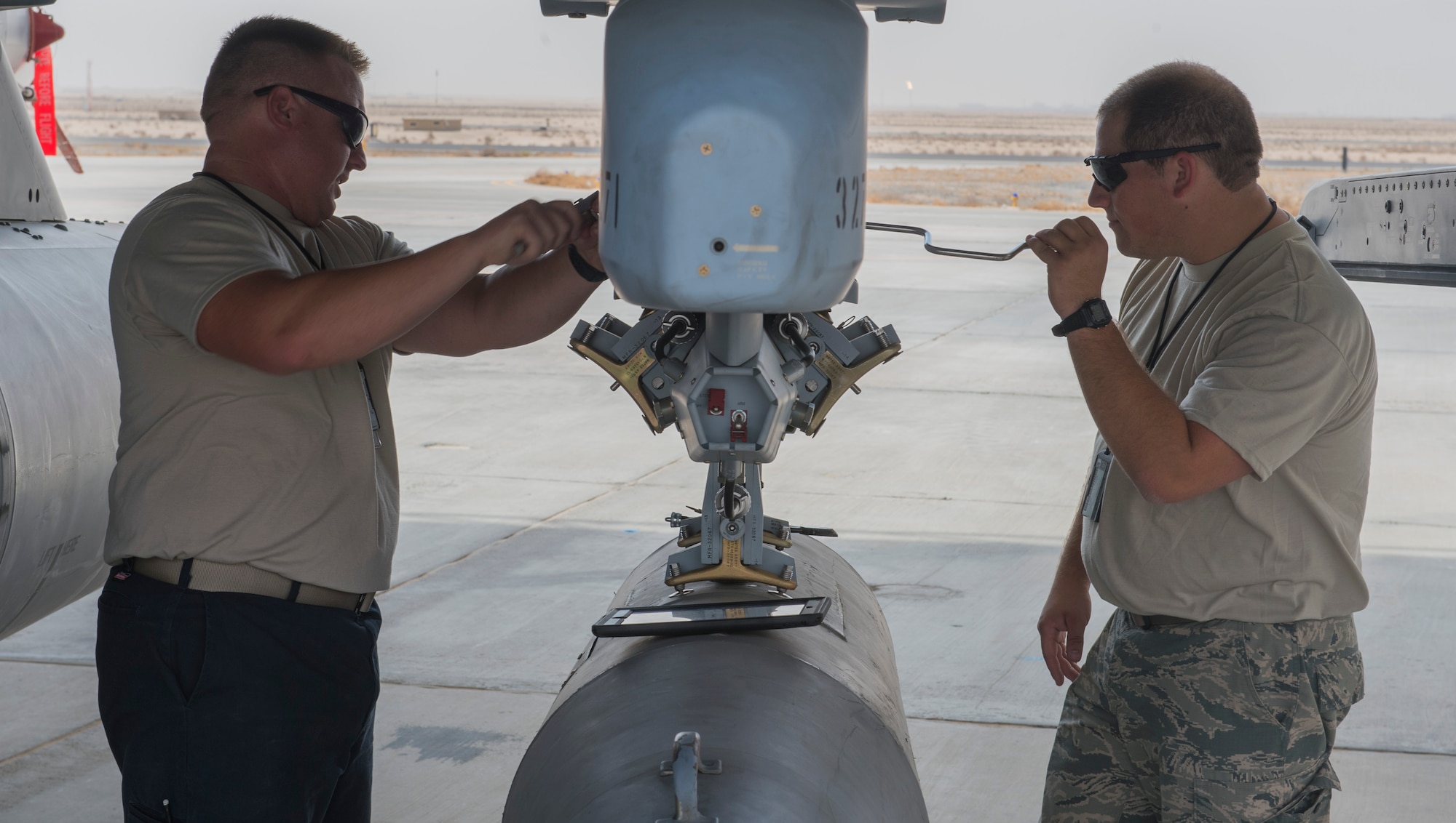 U.S. Air Force Tech. Sgt. J.C. Baxley (left) and Senior Airman Logan Hanea, 100th Fighter Squadron crew chiefs, remove the travel pod from an F-16 Fighting Falcon at the 407th Air Expeditionary Group in Southwest Asia, Oct. 18, 2017. Travel pods are repurposed fuel tanks converted for pilot cargo storage during long flights, typically cross country or deployments. (U.S. Air Force photo by Staff Sgt. Sean Martin/Released)