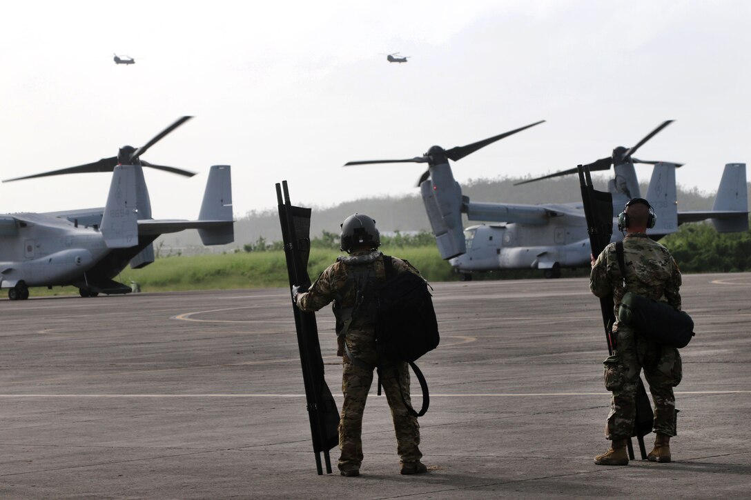 Two soldiers stand watching aircraft in flight.