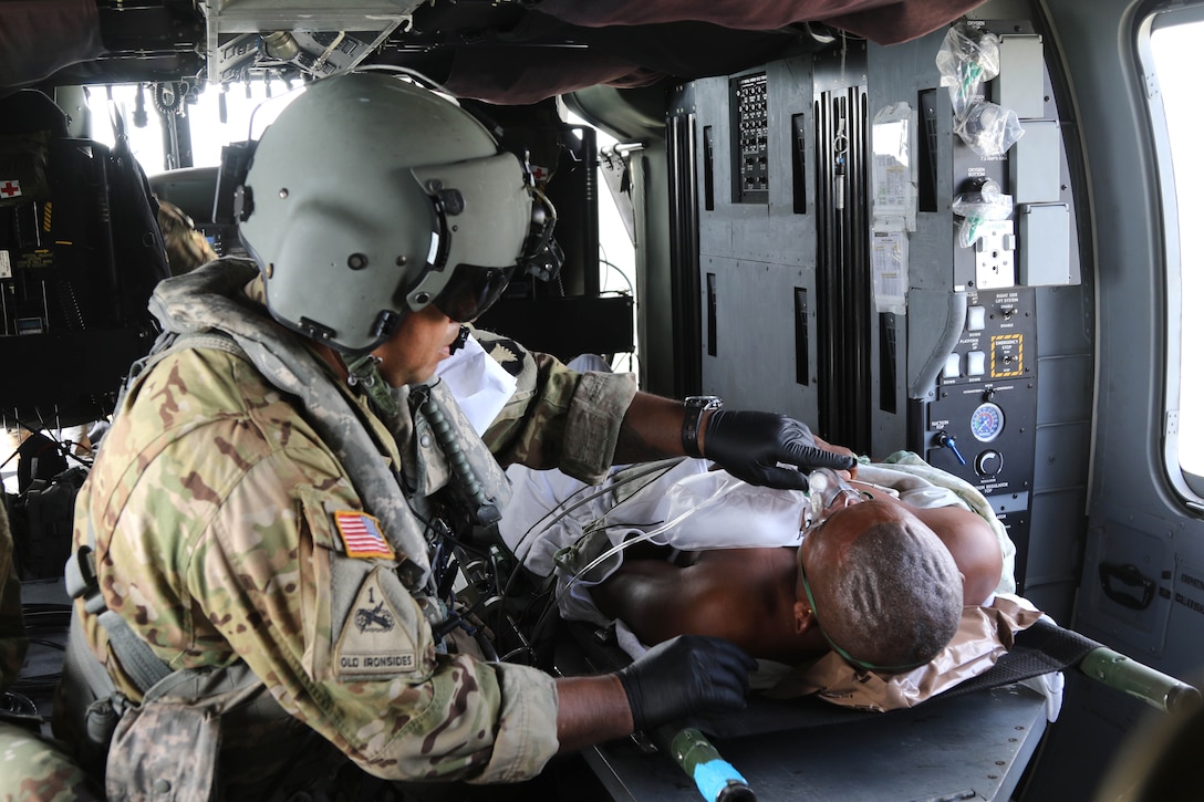 A soldier provides medical care to a patient on a helicopter.