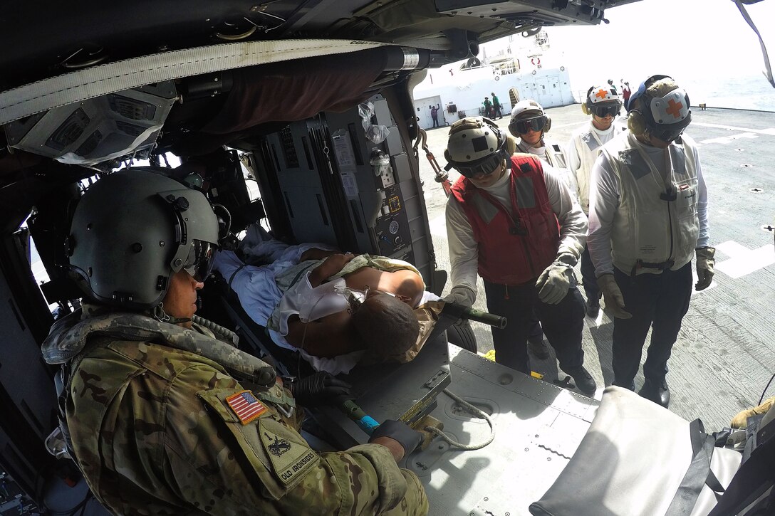 A patient is laying in a helicopter surrounded by others.