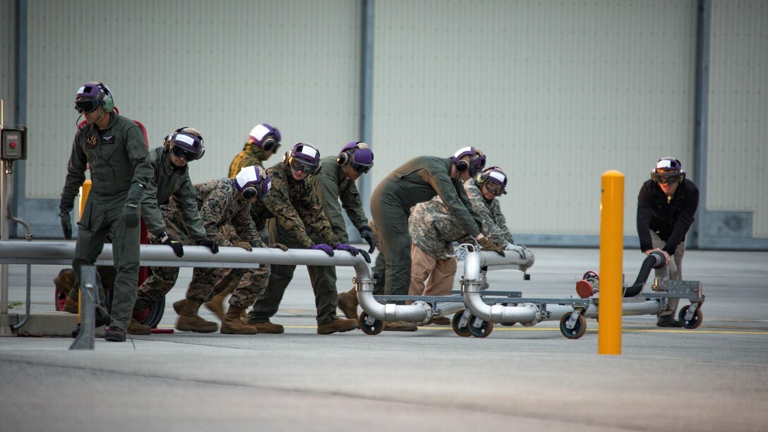 U.S. Marines and Master Labor Contractors with the Logistics Department Fuels Division fold in the Aircraft Direct Fueling System