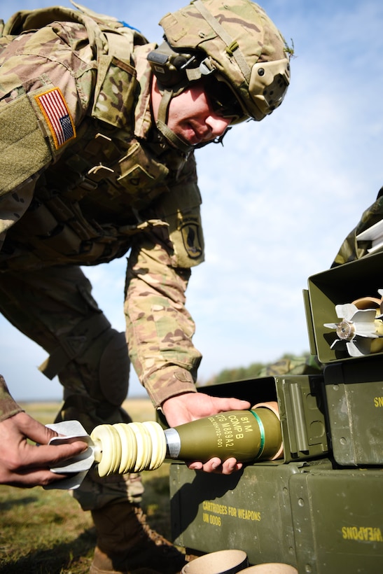 A soldier places a round into a mortar system.