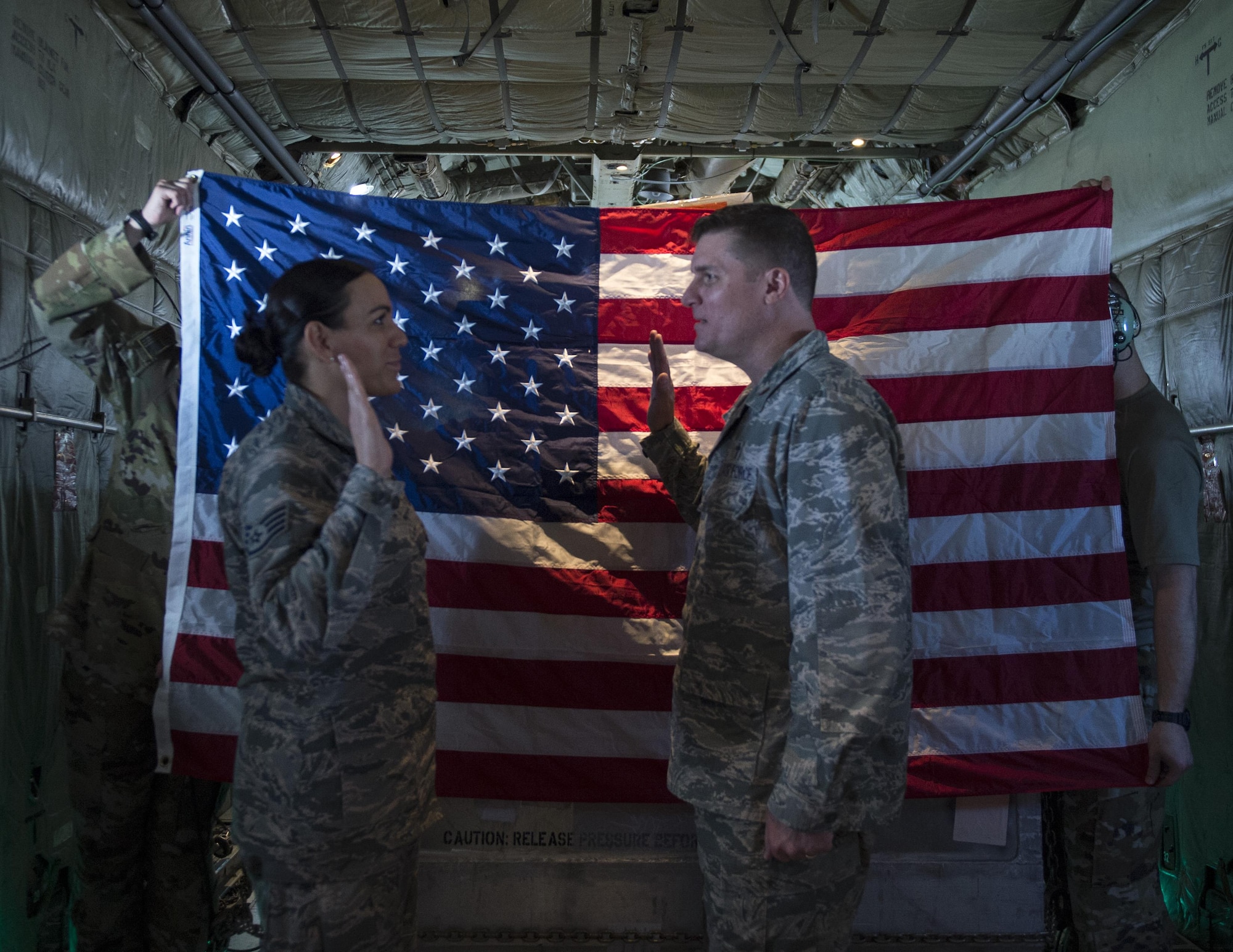 In the cargo bay of a C-130 Hercules from the 911th Airlift Wing, Pittsburgh Air Reserve Station, two loadmasters hold up a U.S. flag.