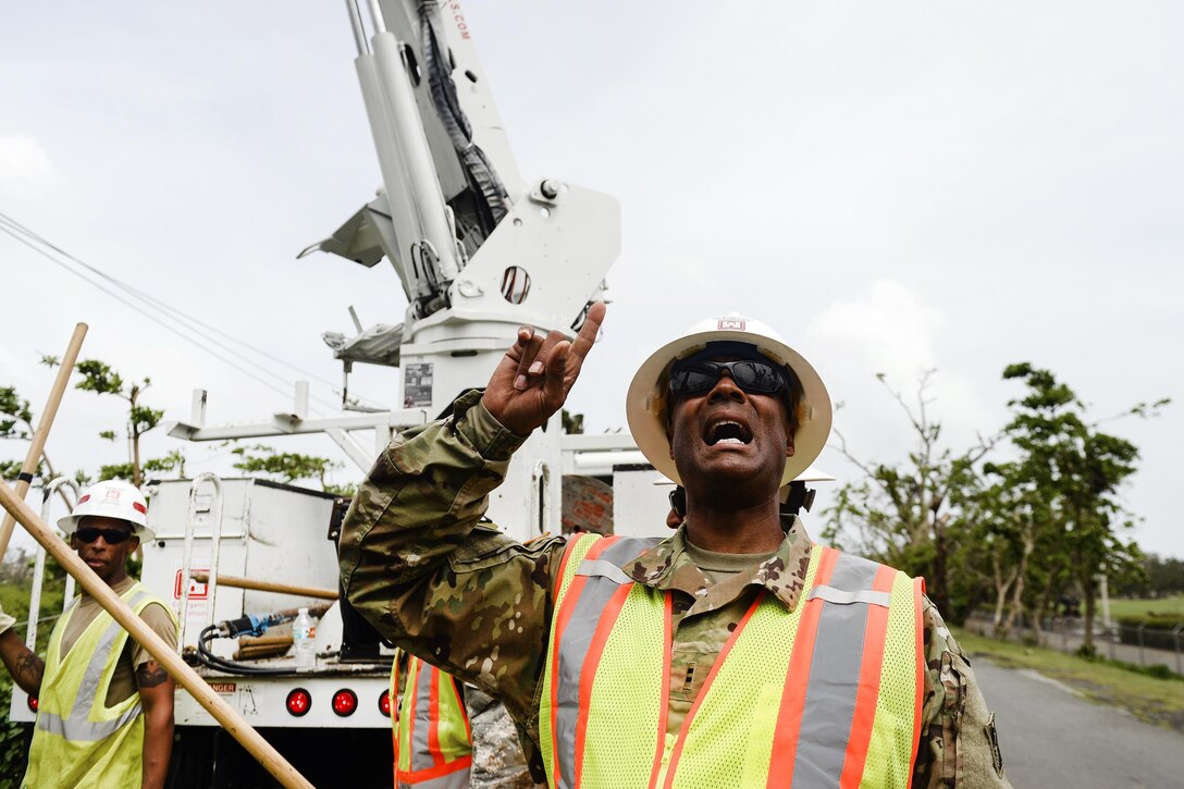 An Army reservist directs his team as they prepare to set a power pole.