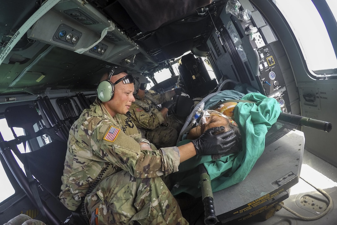 An Army surgeon comforts a patient on a helicopter.