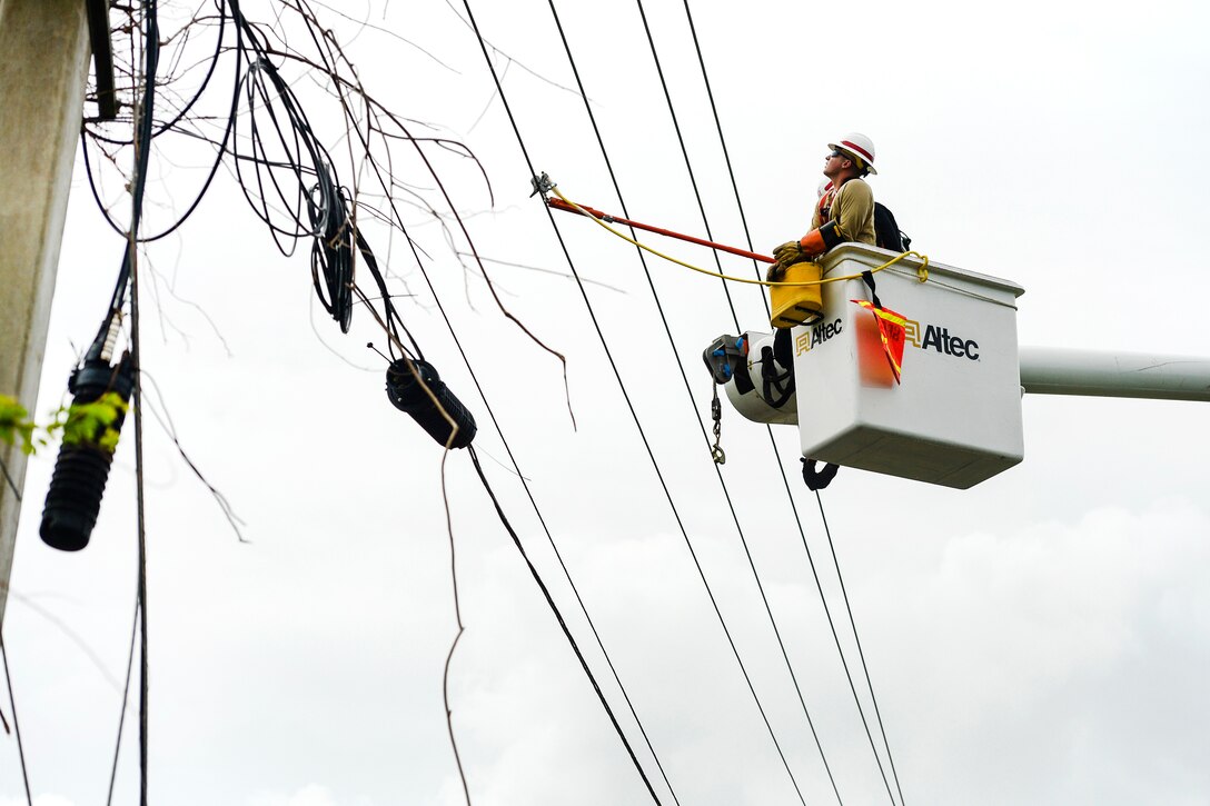 Army Reservists attach grounding cables to power lines in Puerto Rico.