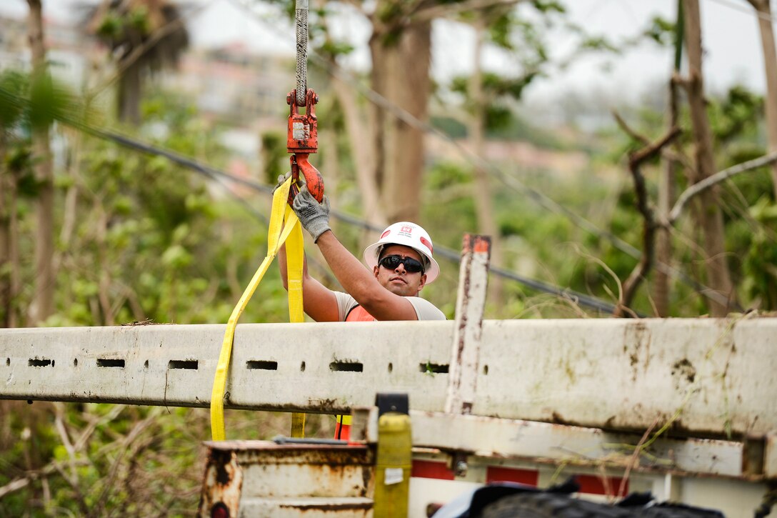 An Army Reservist attaches a nylon strap to a hoist cable in Puerto Rico.