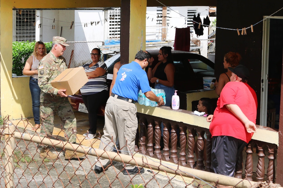A military commander delivers a box of supplies to hurricane victims in Puerto Rico.
