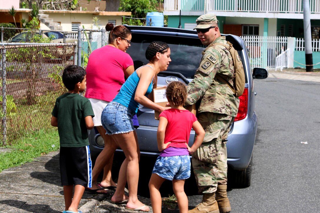 A soldier distributes food and water to residents in Puerto Rico.