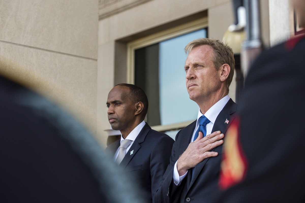 The deputy defense secretary stands with his hand over his heart during a ceremony.
