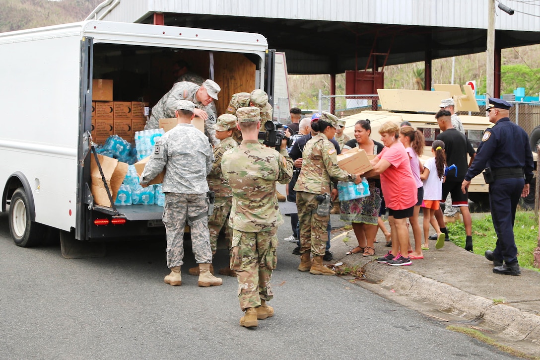 Soldiers offload food and water from a truck for residents in Puerto Rico.