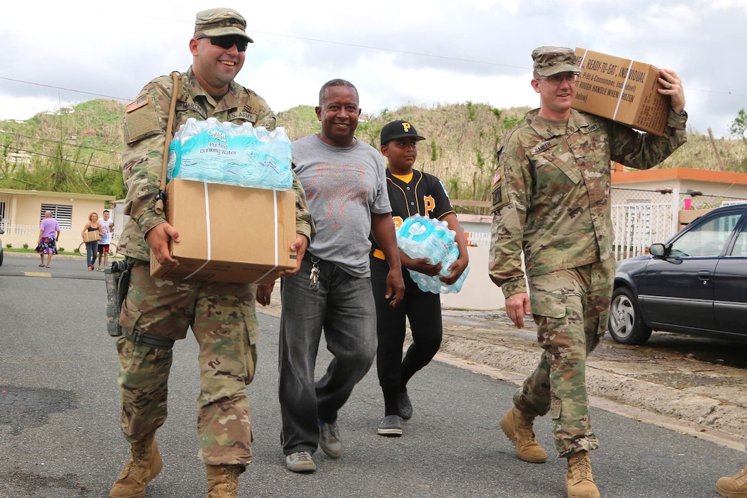 Soldiers and volunteers carry food and water for residents in Puerto Rico.