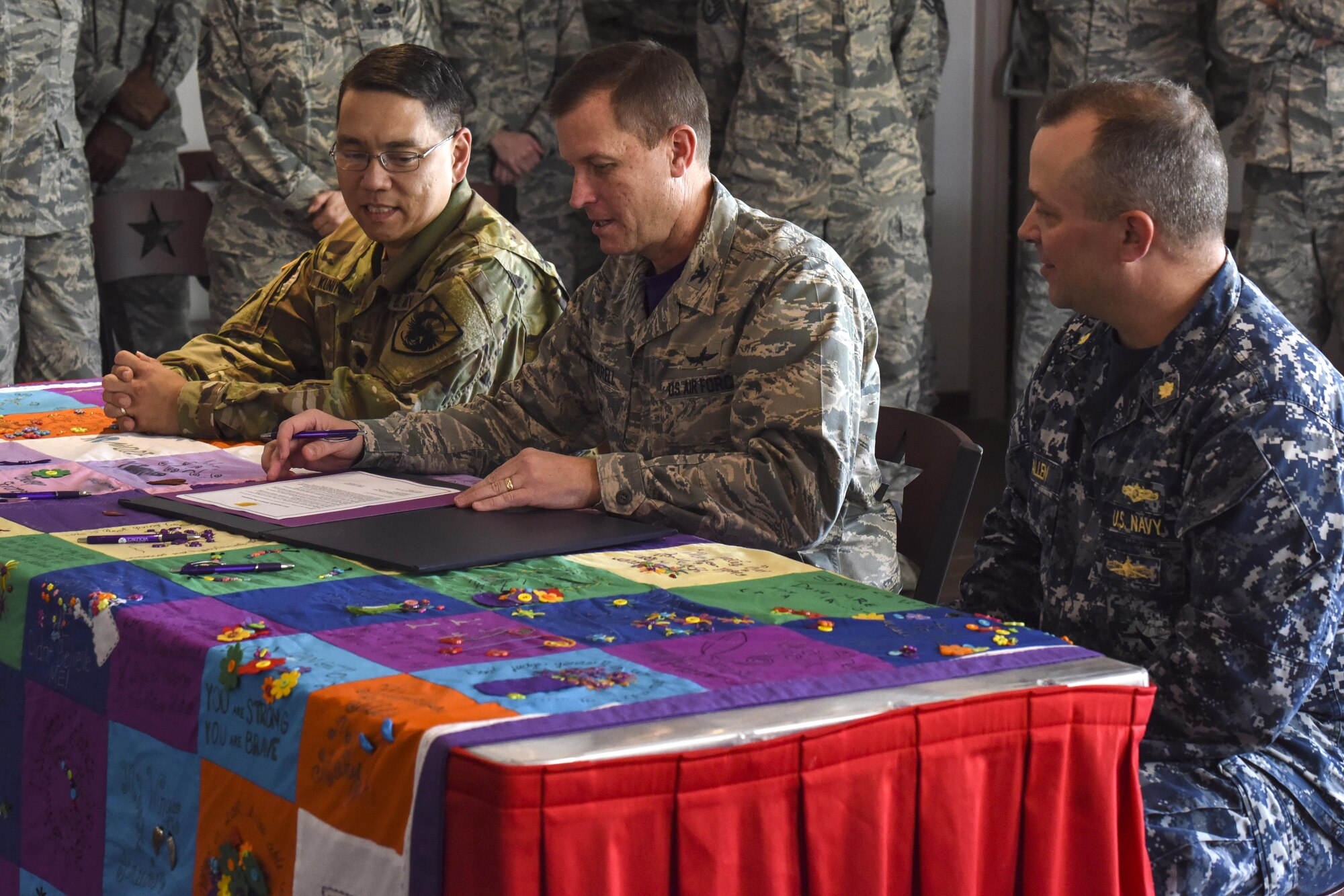 Lt. Col. Yukio Kuniyuki, 344th Military Intelligence Battalion commander, Col. Jeffrey Sorrell, 17th Training Wing vice commander, and Lt. Cmdr. Christopher Allen, Center for Information Warfare Training Detachment Goodfellow officer in charge, sign the Domestic Violence Awareness Month proclamation at the Event Center on Goodfellow Air Force Base, Texas, Oct. 20, 2017. The signing of the proclamation showed the joint forces stance against abuse. (U.S. Air Force photo by Airman 1st Class Zachary Chapman/Released)