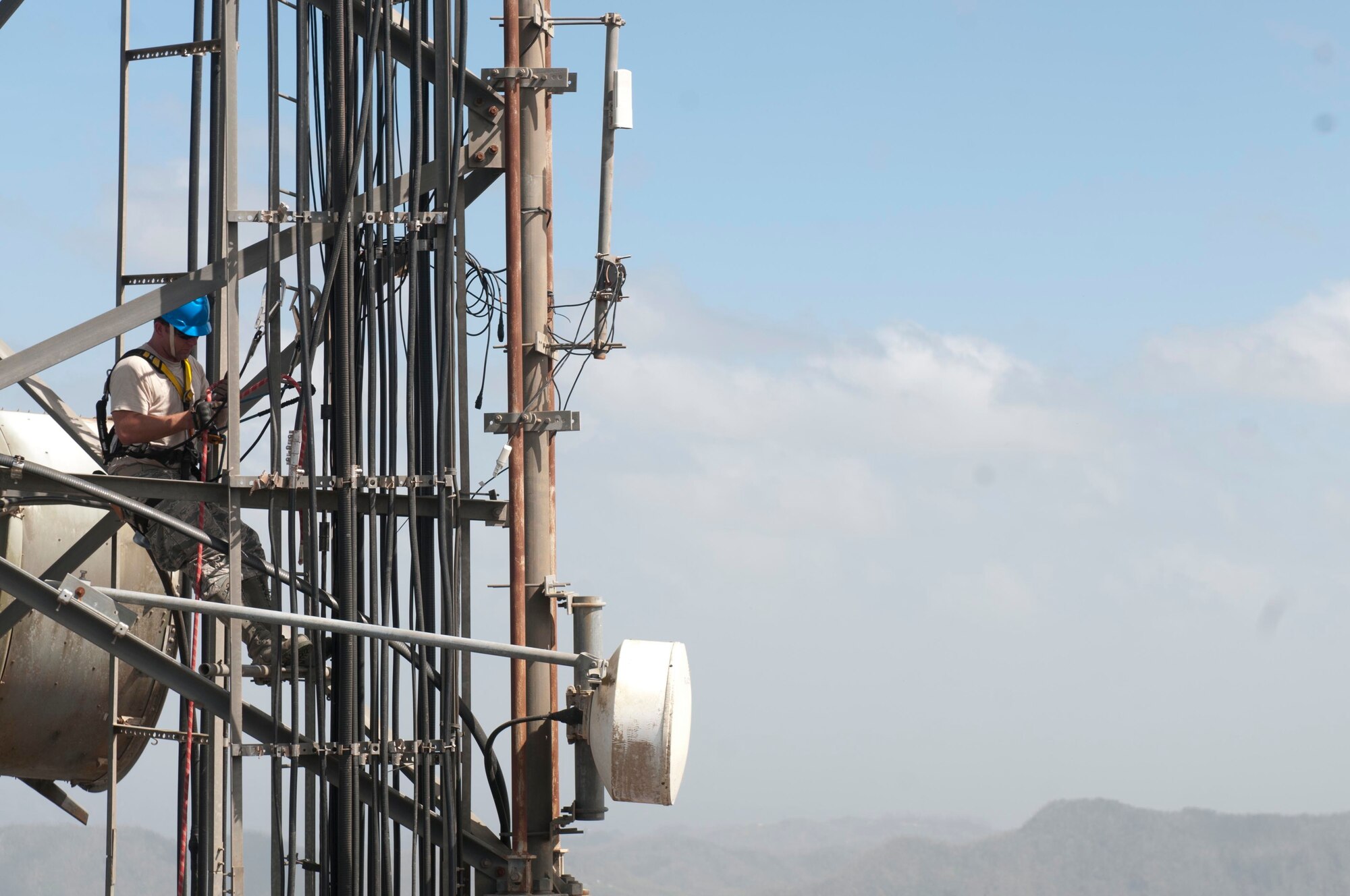 An airman with the 85th Engineering and Installation Squadron, 38th Cyberspace Engineering Installation Group, 688th Cyberspace Wing from Keesler Air Force Base, Mississippi hooks up a safety line on a radio tower October 20, 2017 at Cerro de Punta mountain near Ponce, Puerto Rico. The 85th EIS are working to reestablish and improve radio communications for local emergency personnel and first responders across the island.