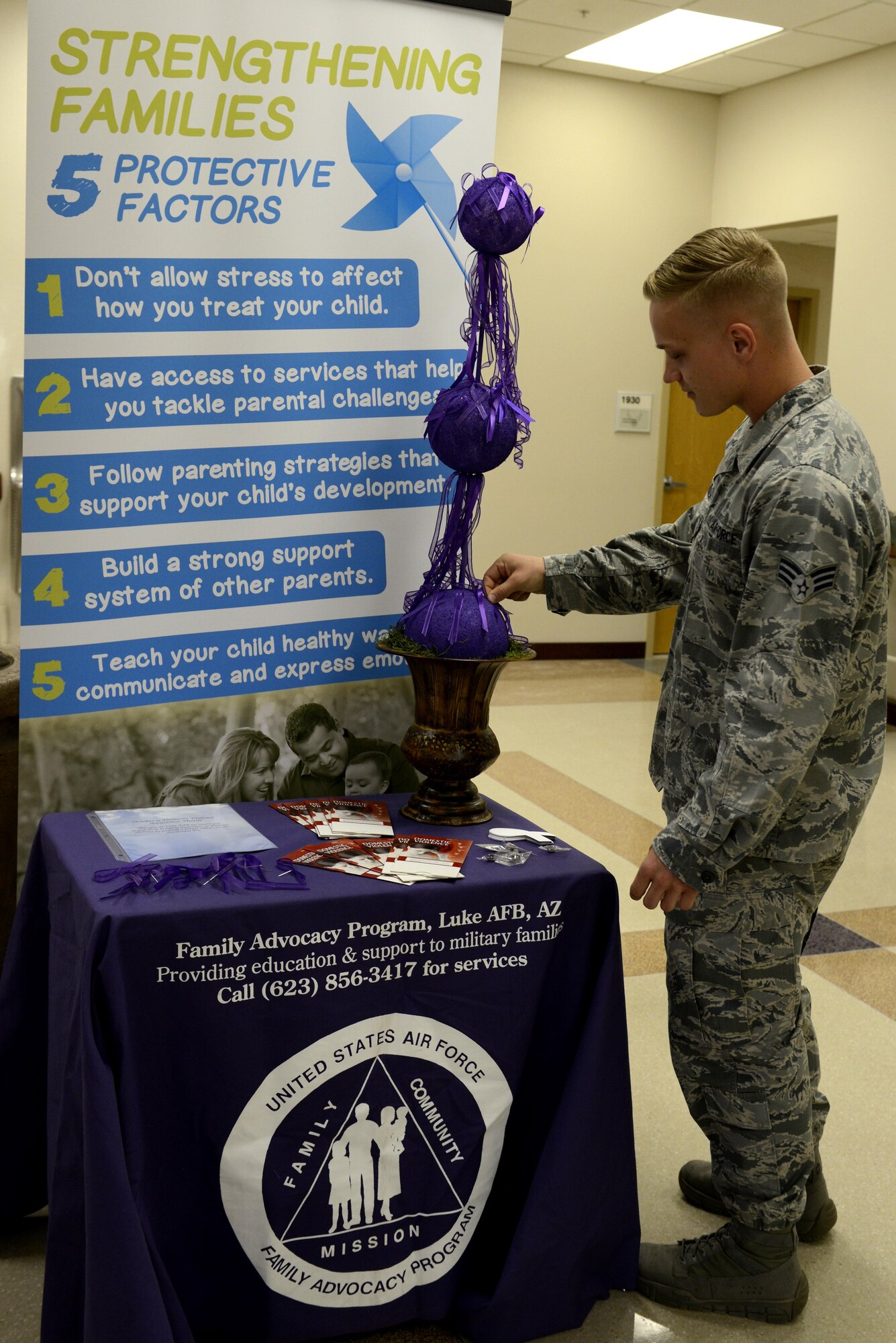 Senior Airman John Schwanterlik, 56th Medical Support Squadron out-patient records technician, pins a purple ribbon on a Domestic Violence Awareness Month pot at Luke Air Force Base, Ariz., Oct. 20, 2017.  Purple is the dedicated color to honor domestic violence awareness month.  (U.S. Air Force photo/Airman 1st Class Pedro Mota)