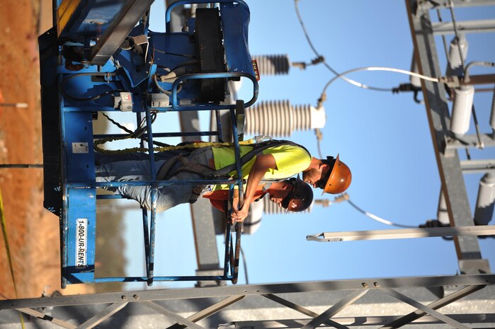 Contractors raise themselves up to work on an electrical substation at Beale Air Force Base