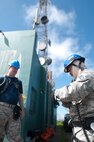 Capt. Ryan Headrick with the 85th Engineering and Installation Squadron, 38th Cyberspace Engineering Installation Group, 688th Cyberspace Wing from Keesler Air Force Base, Mississippi observes an airman checking his safety harness October 20, 2017 at Cerro de Punta mountain near Ponce, Puerto Rico. The 85th EIS are working to reestablish and improve radio communications for local emergency personnel and first responders across the island.
