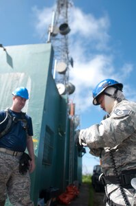 Capt. Ryan Headrick with the 85th Engineering and Installation Squadron, 38th Cyberspace Engineering Installation Group, 688th Cyberspace Wing from Keesler Air Force Base, Mississippi observes an airman checking his safety harness October 20, 2017 at Cerro de Punta mountain near Ponce, Puerto Rico. The 85th EIS are working to reestablish and improve radio communications for local emergency personnel and first responders across the island.