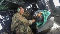An Army surgeon comforts a patient on a helicopter.