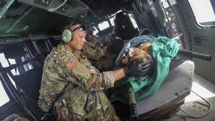 An Army surgeon comforts a patient on a helicopter.