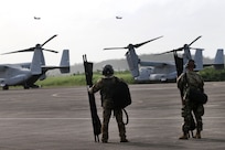 Two soldiers stand watching aircraft in flight.