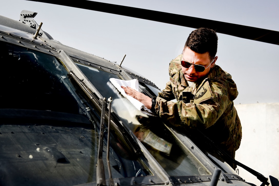 Senior Airman Brandon McLaughlin wipes down the cockpit window on an HH-60 Pave Hawk helicopter.