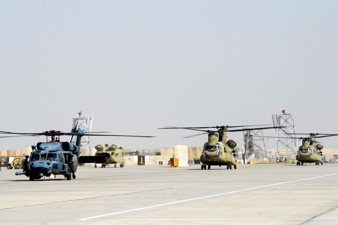 An Air Force HH-60 Pave Hawk and two Army CH-47 Chinook helicopters prepare for takeoff.
