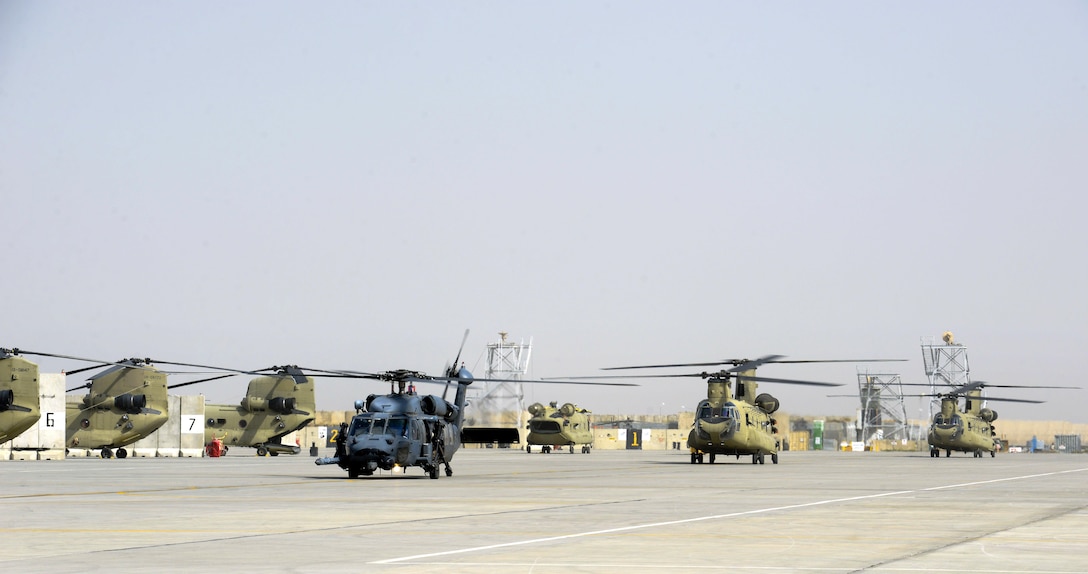 An Air Force HH-60 Pave Hawk and two Army CH-47 Chinook helicopters prepare for takeoff.