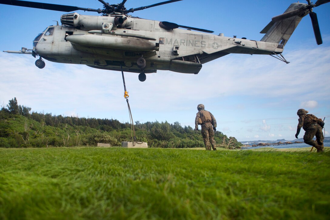 A CH-53E Super Stallion helicopter lifts a cement block during an external lift drill.