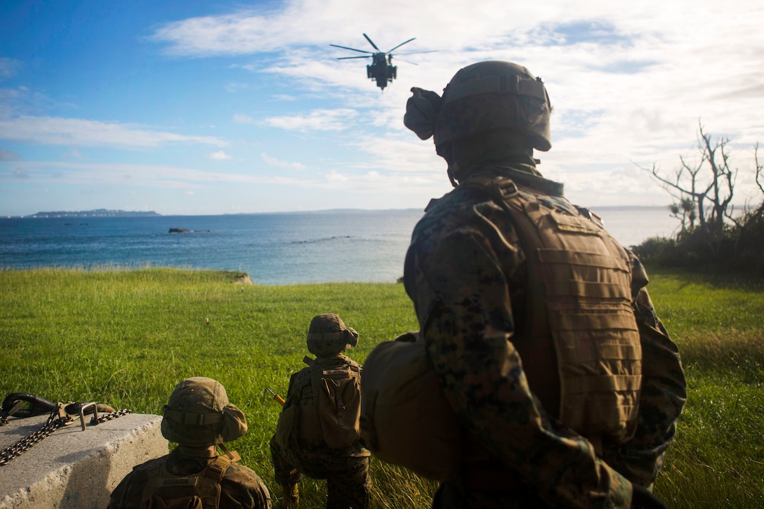 Marines await an approaching a CH-53E Super Stallion helicopter before hooking up a cement block while conducting external lift drills.