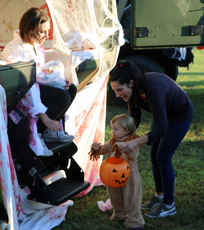 Christina Carmody, left, hands Tilly, 2, a piece of candy during a Trunk or Treat event at Marine Corps Air Station Cherry Point, N.C., Oct. 19, 2017. Marine Corps Community Services hosted the Halloween-inspired event that included face painting; touch-the-truck displays; and a family glow dance party. Decorated trunks were judged and the highest-rated contestants received door prizes. (U.S. Marine Corps photo by Pfc. Andrew King/ Released)