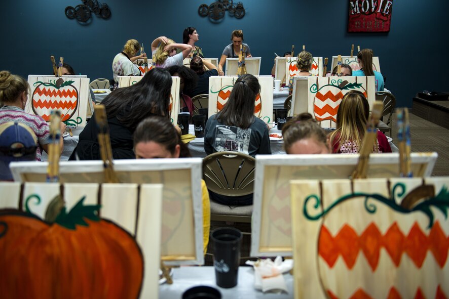 Participants work on their paintings during a Painting with a Twist event, Oct. 21, 2017, at Moody Air Force Base, Ga. At the event, participants went through the steps to paint a festive fall pumpkin.  The event was geared toward providing fun painting experiences for Active Duty members and their dependents, which can help ease some of the stress they face as military families. During the event, participants went through the steps to paint a festive fall pumpkin.  (U.S. Air Force photo by Airman 1st Class Erick Requadt)