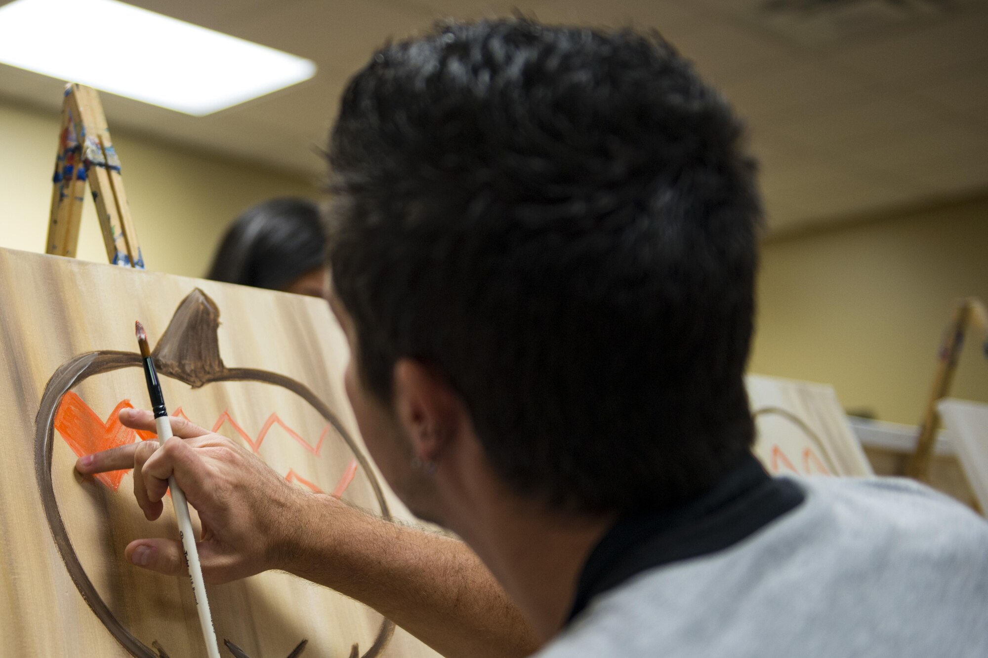 Michael Rust, a military spouse, rubs orange paint on a canvas during a Painting with a Twist event, Oct. 21, 2017, at Moody Air Force Base, Ga. The event was geared toward providing fun painting experiences for Active Duty members and their dependents, which can help ease some of the stress they face as military families. During the event, participants went through the steps to paint a festive fall pumpkin.  (U.S. Air Force photo by Airman 1st Class Erick Requadt)