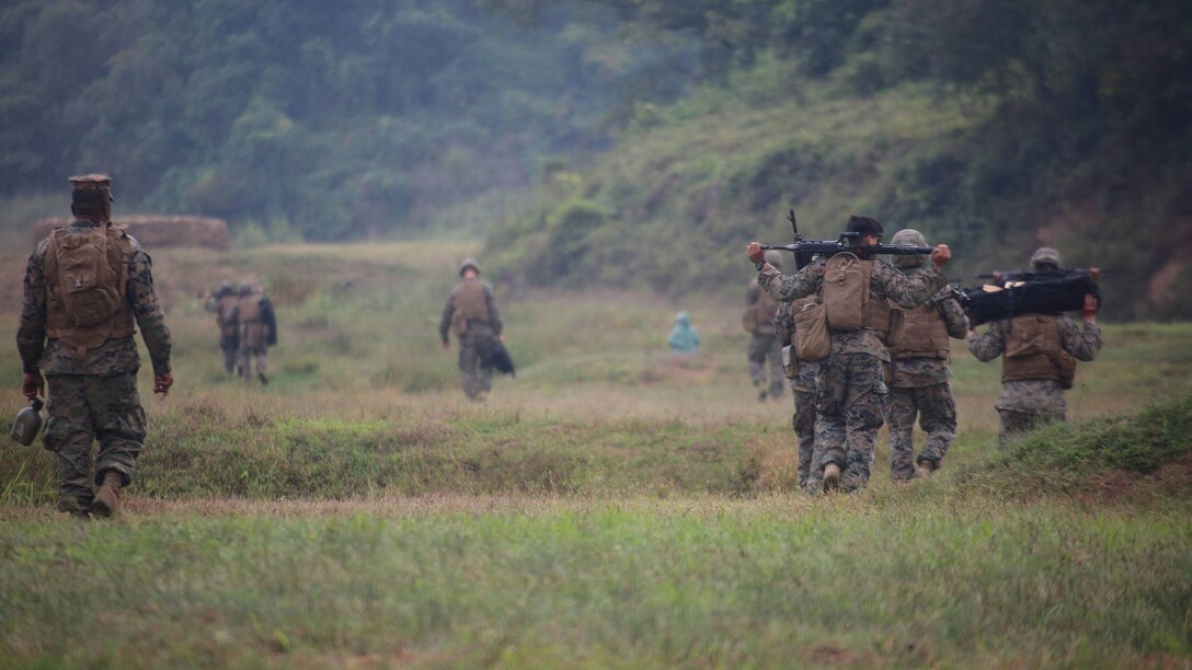 Marines with Marine Air Support Squadron 2, Marine Air Control Group 18, Marine Aircraft Group 36, 1st Marine Aircraft Wing, walk across a field