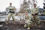 California Guard Soldiers nurture a tree amid fire ruins