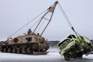 An M88 Armored Recovery Vehicle lifts a truck on snow.
