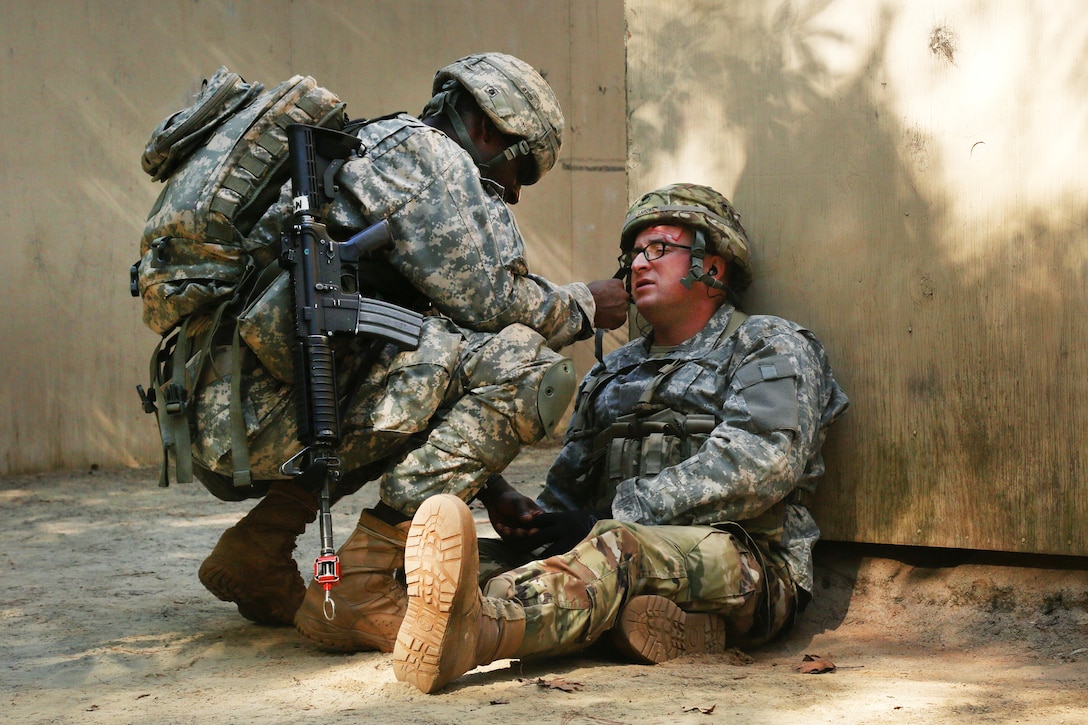 A soldier performs tactical field medical care on a mock patients head wound during the Expert Field Medical Badge testing.