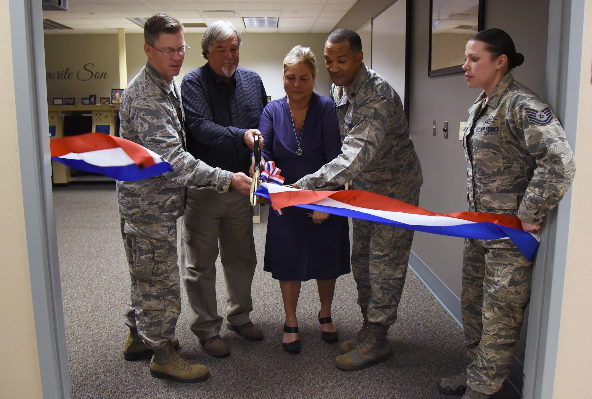 Col. C. Mike Smith, 81st Training Wing vice commander (left), and Lt. Col. Billy Wilson (right), 334th Training Squadron commander, assist Suzi Fernandez and Brent Sibley with cutting a ribbon to a training room during a dedication ceremony to honor their son, Staff Sgt. Forrest Sibley, at Cody Hall Oct. 20, 2017, on Keesler Air Force Base, Mississippi. Sibley was killed in combat in Afghanistan on Aug. 26, 2015. Sibley, a four-time Bronze Star medal recipient, was a combat controller who received his initial technical training from the 334th Training Squadron here. (U.S. Air Force photo by Kemberly Groue)