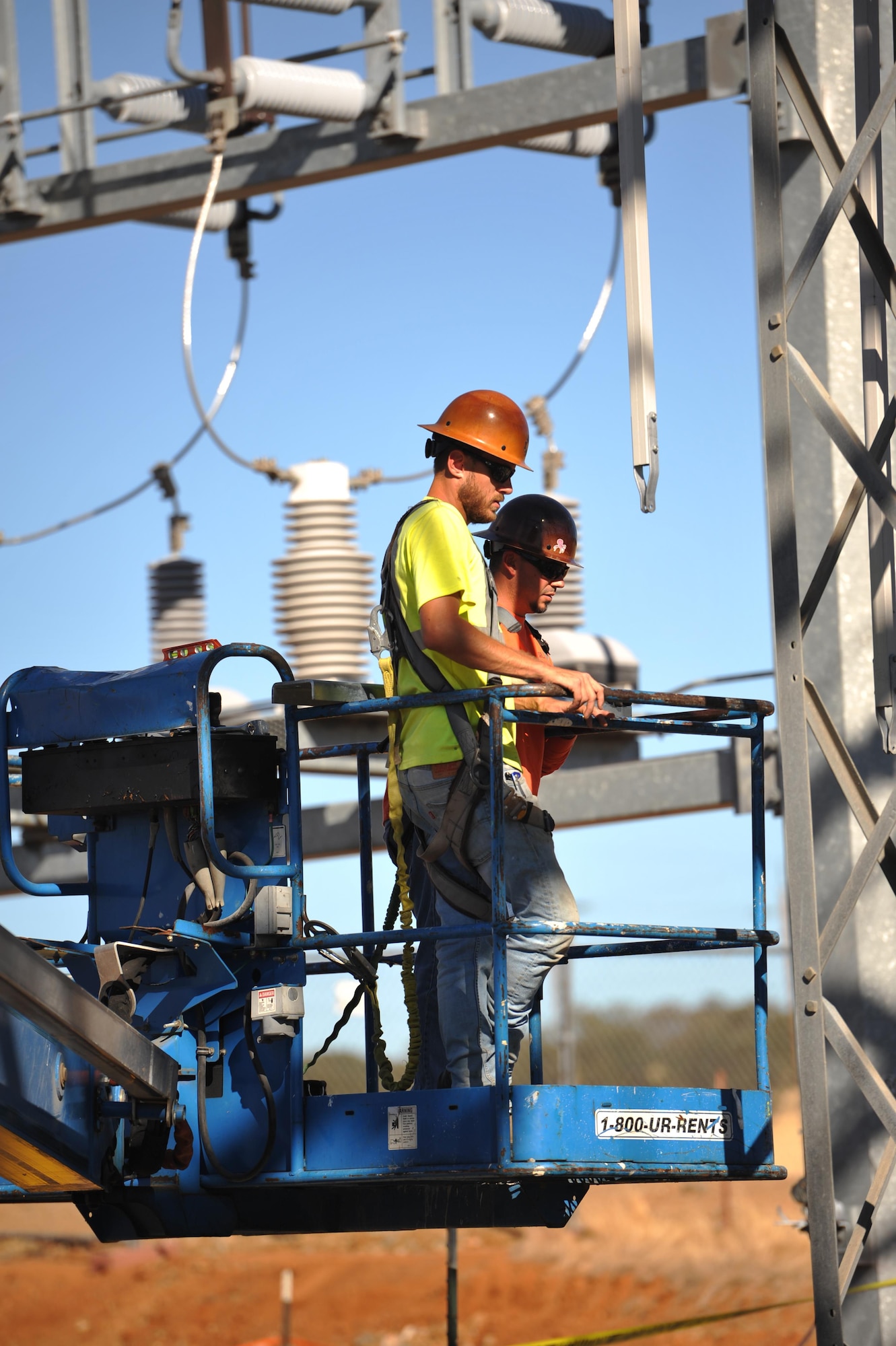 Contractors raise themselves up to work on an electrical substation at Beale Air Force Base