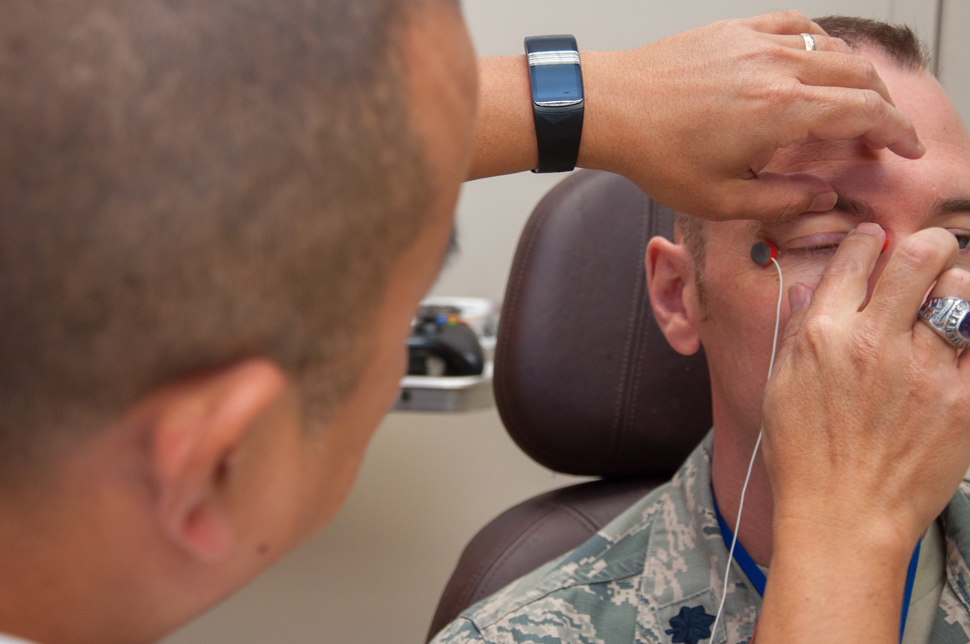 Dino Tsuchiyama (left), Aeromedical Consultation Service Ophthalmology Branch electro-diagnostic technician, attaches electrodes to Lt. Col. Christopher Cannon in order to measure how well the retinas in Cannon’s eyes react to light. Ophthalmological electrophysiology studies the electrical activity of the eyes. (U.S. Air Force photo/John Harrington)