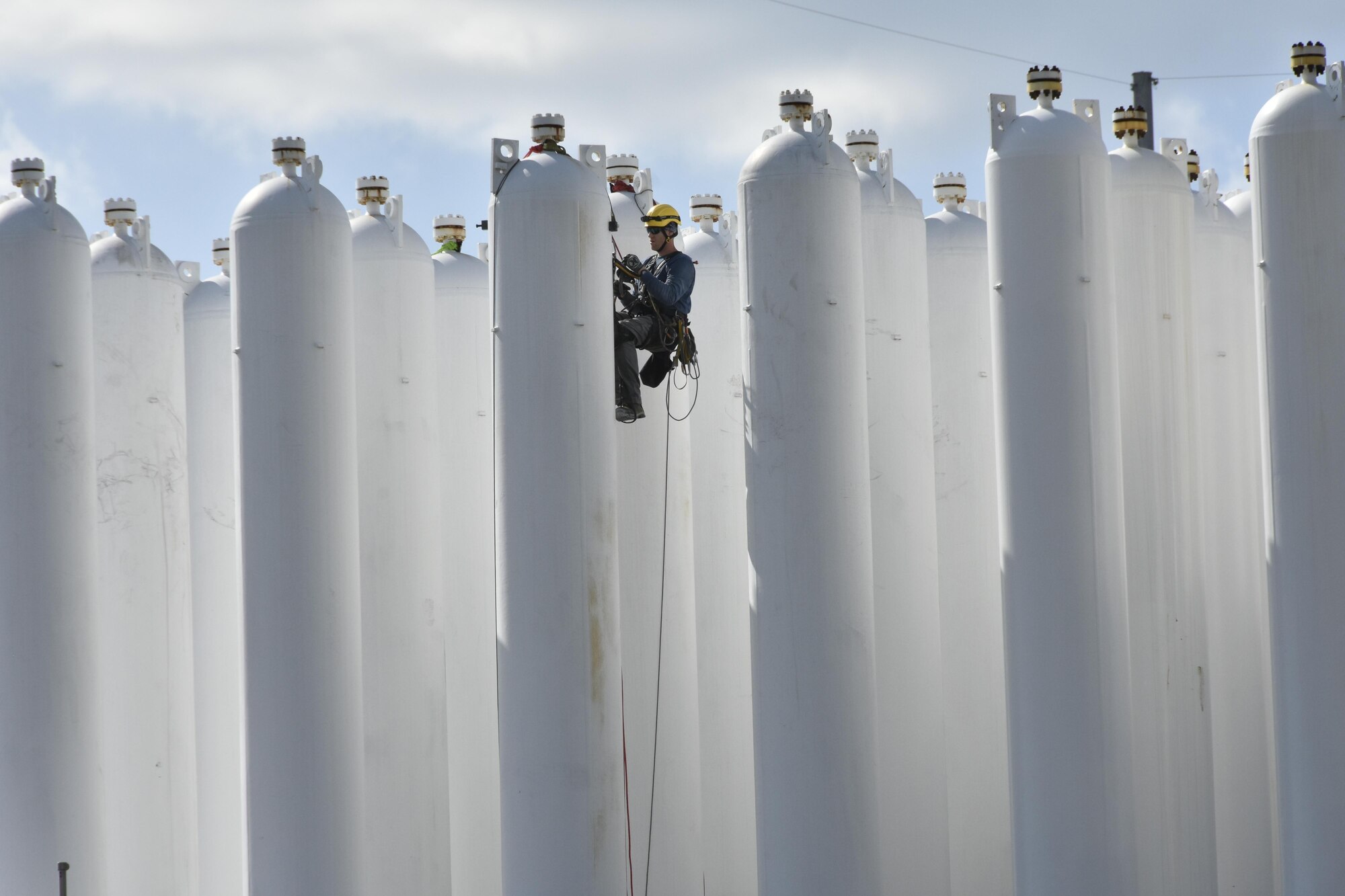 A new technique was recently used at the AEDC Aerodynamic and Propulsion Test Unit (APTU) at Arnold Air Force Base for inspecting the high pressure air storage vessels. An outside contractor was hired and members of a rope crew set sensors on the large bottles at APTU to detect flaws. Pictured is a member of the rope crew placing a sensor on one of the bottles. (U.S. Air Force photo/Rick Goodfriend)