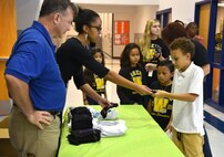 Joe Angermeier and Quinn Green, program managers with the 38th Cyberspace Engineering Group’s Requirements Implementation Section, hand out a new pair of socks to students at Wheeler Elementary Oct. 6.